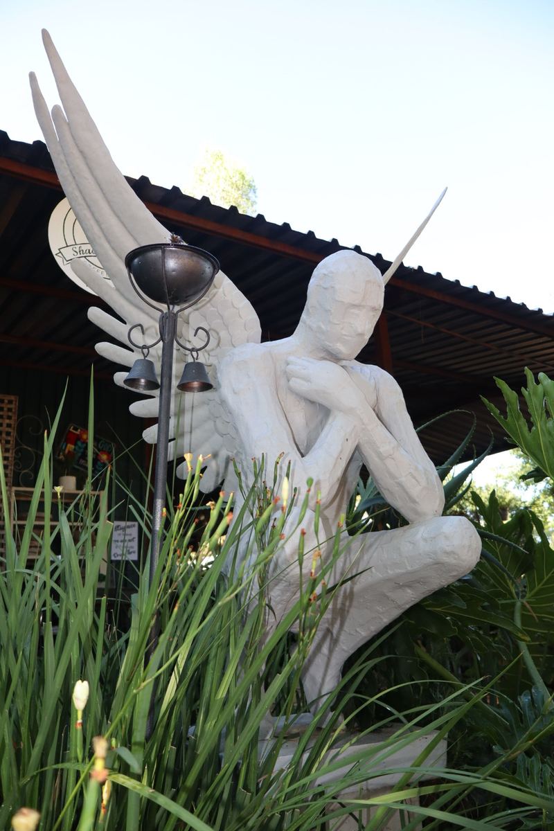 Winged angel figure sculpture in a garden setting